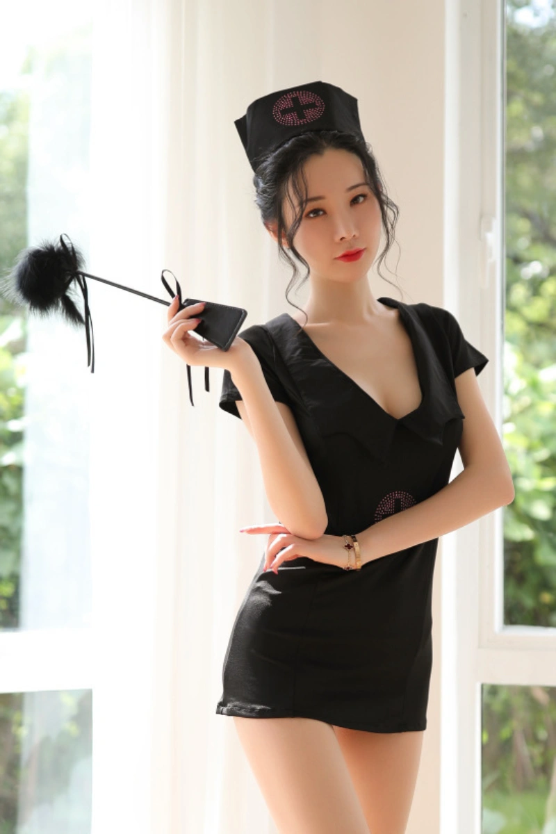 Woman posing in black nurse costume with hat, holding playful accessory