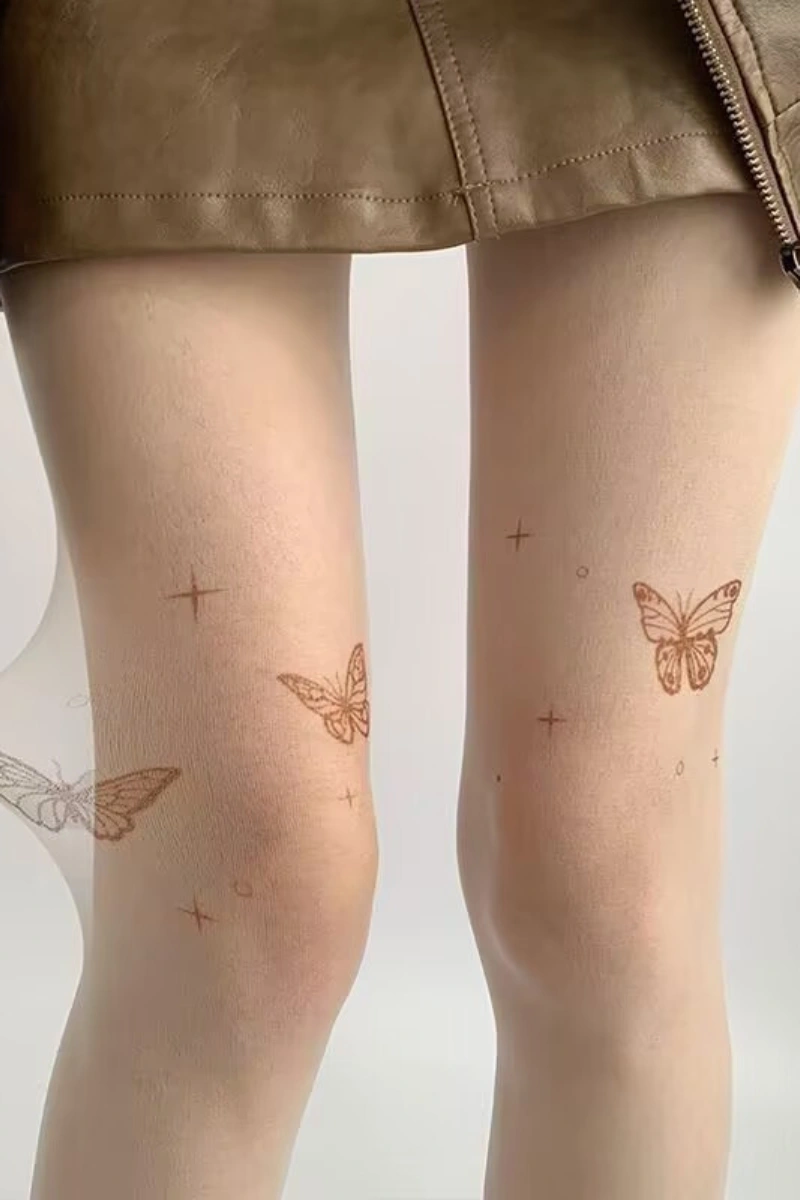 Legs wearing embroidered silk stockings with butterfly embroidery in nude sheer fabric.