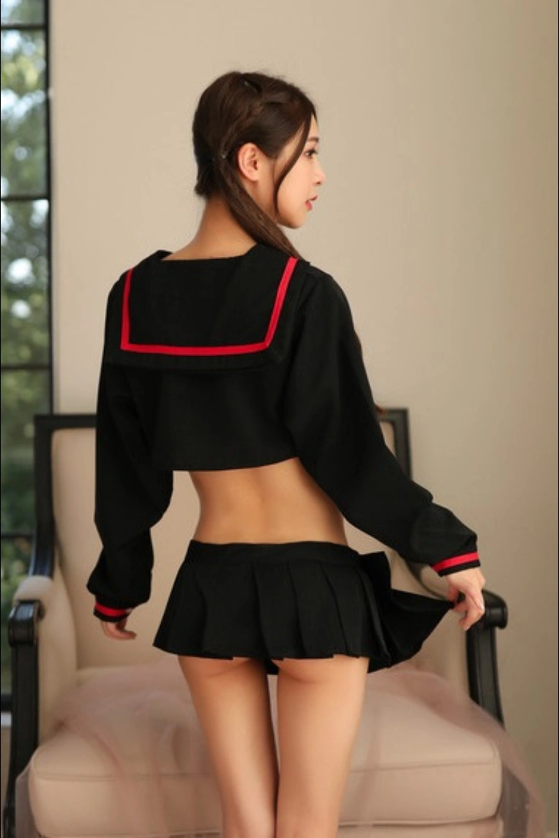 Model wearing a JK school uniform costume in black with long sleeves, sailor collar, and red trim, showing the back design.