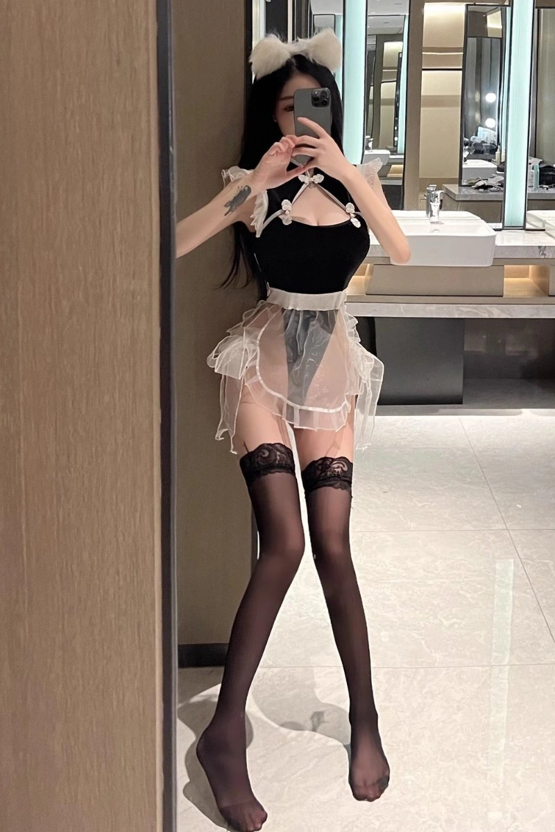 Woman posing in a black b2b cheongsam lingerie set with sheer apron and cat ear accessory.