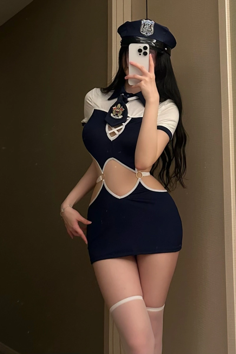 Model wearing a Sexy Police Roleplay Costume featuring a navy blue mini dress with side cutouts, white trim, and police cap.