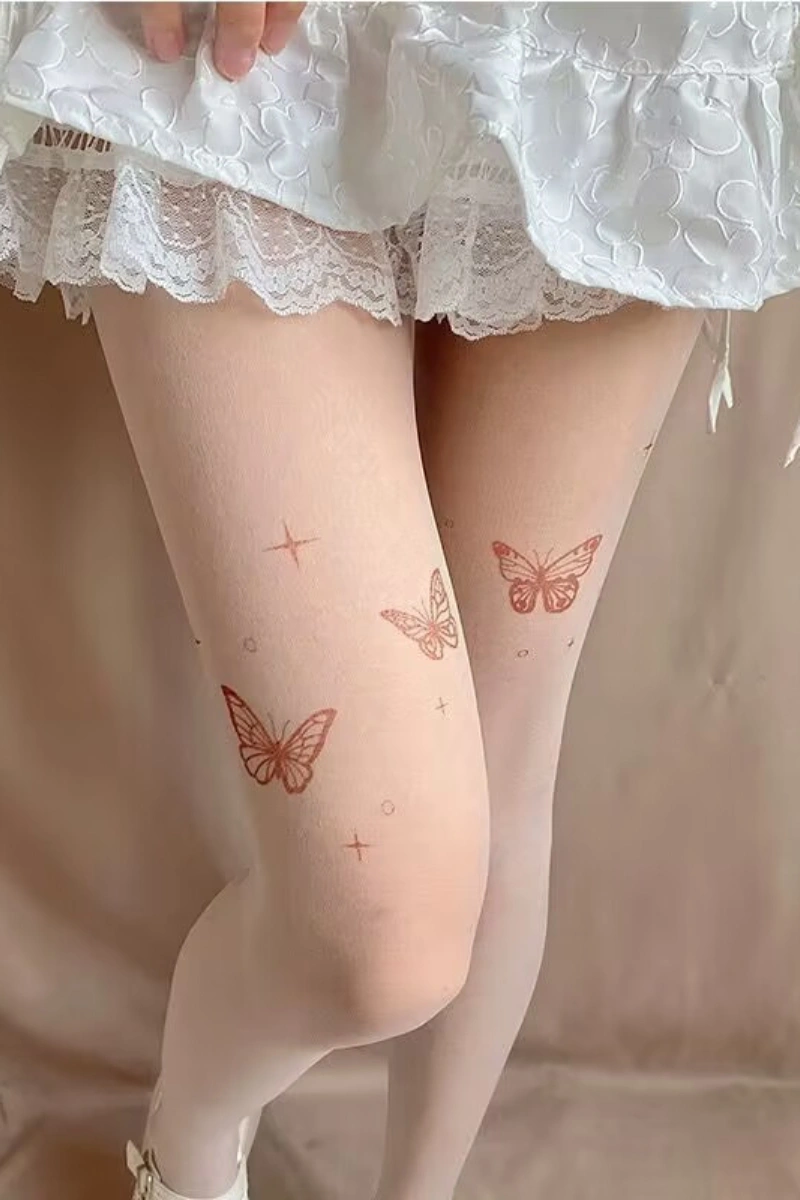 Model in embroidered silk stockings with butterfly embroidery paired with white lace skirt.