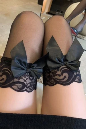 Black silk stockings with lace top featuring satin bows and floral lace design, styled for lingerie fashion.