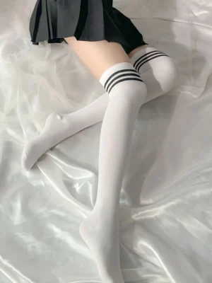 Model in thigh high white silk stockings featuring black stripe elastic top