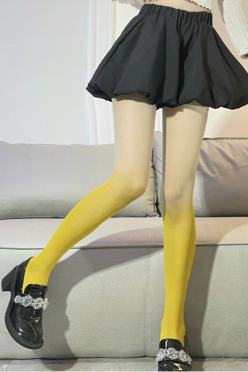 Model showcasing wholesale glossy silk stockings in bright yellow ombre with black skirt.