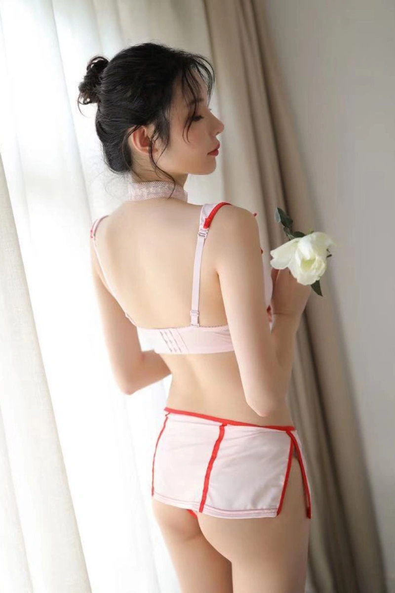 Model in wholesale seductive nurse dress featuring open back and red trim details for sexy appeal