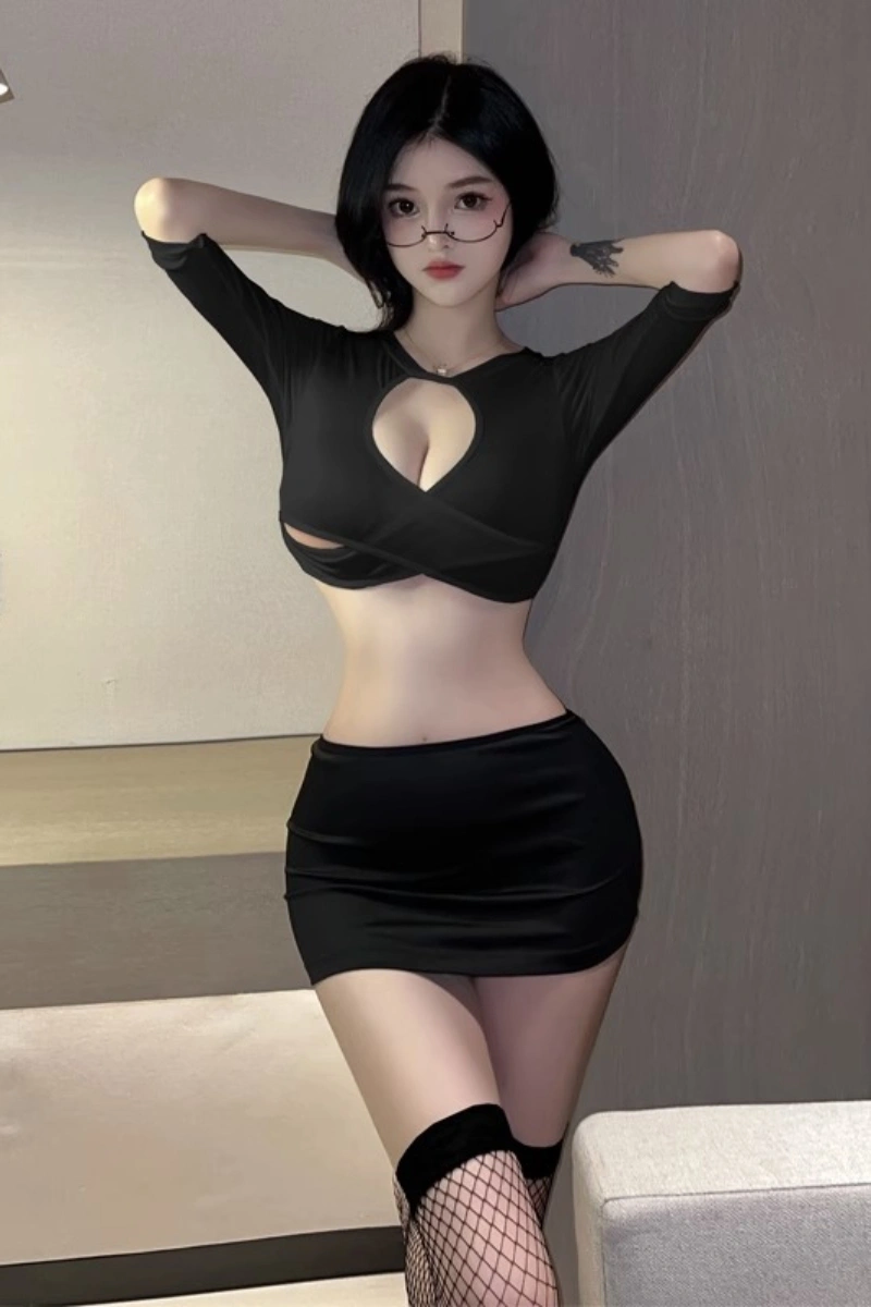 Model posing in black cut-out crop top and skirt, styled with glasses for wholesale sexy secretary roleplay.