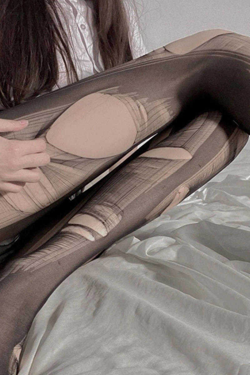 Close-up of wholesale silk stockings erotic ripped pantyhose in sheer black, showing worn distressed style.