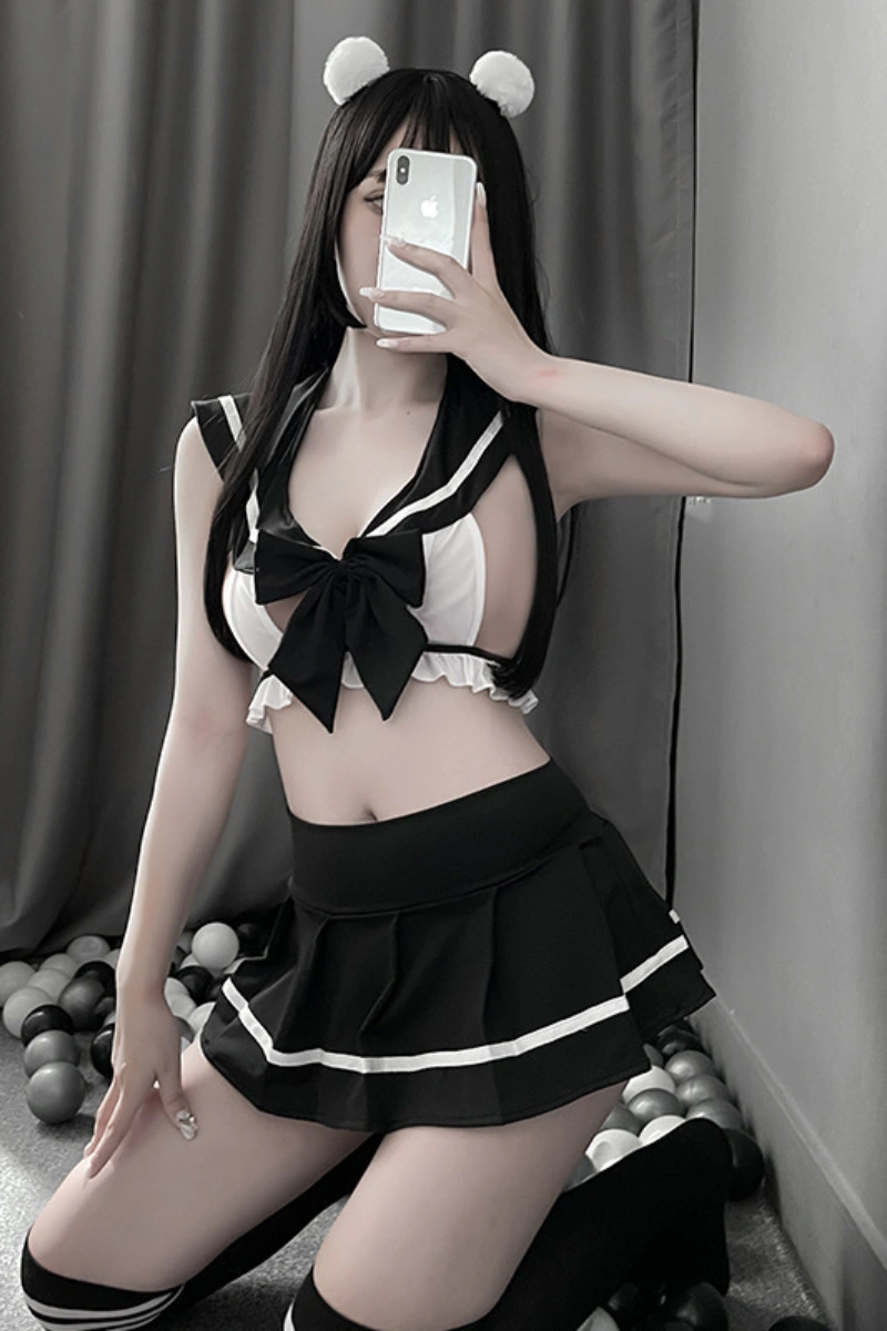 Woman posing in wholesale JK student lingerie with black skirt and bow-tie crop top.