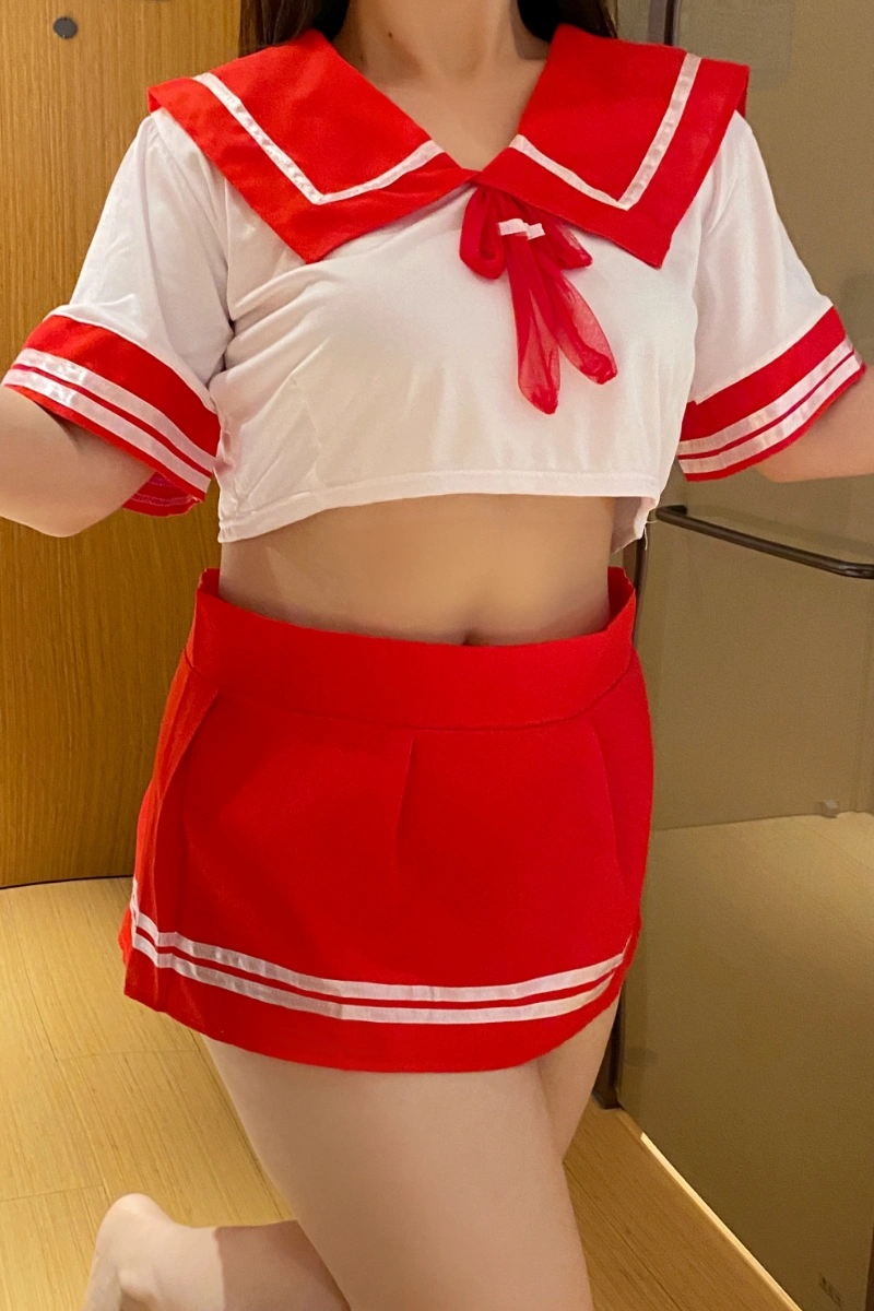 Student uniform costume with white crop top, red sailor collar, bow tie, and pleated mini skirt.