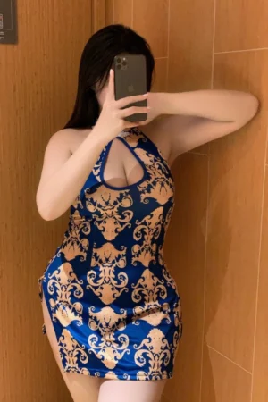 Woman posing in wholesale floral cheongsam lingerie with golden floral patterns and side slit.