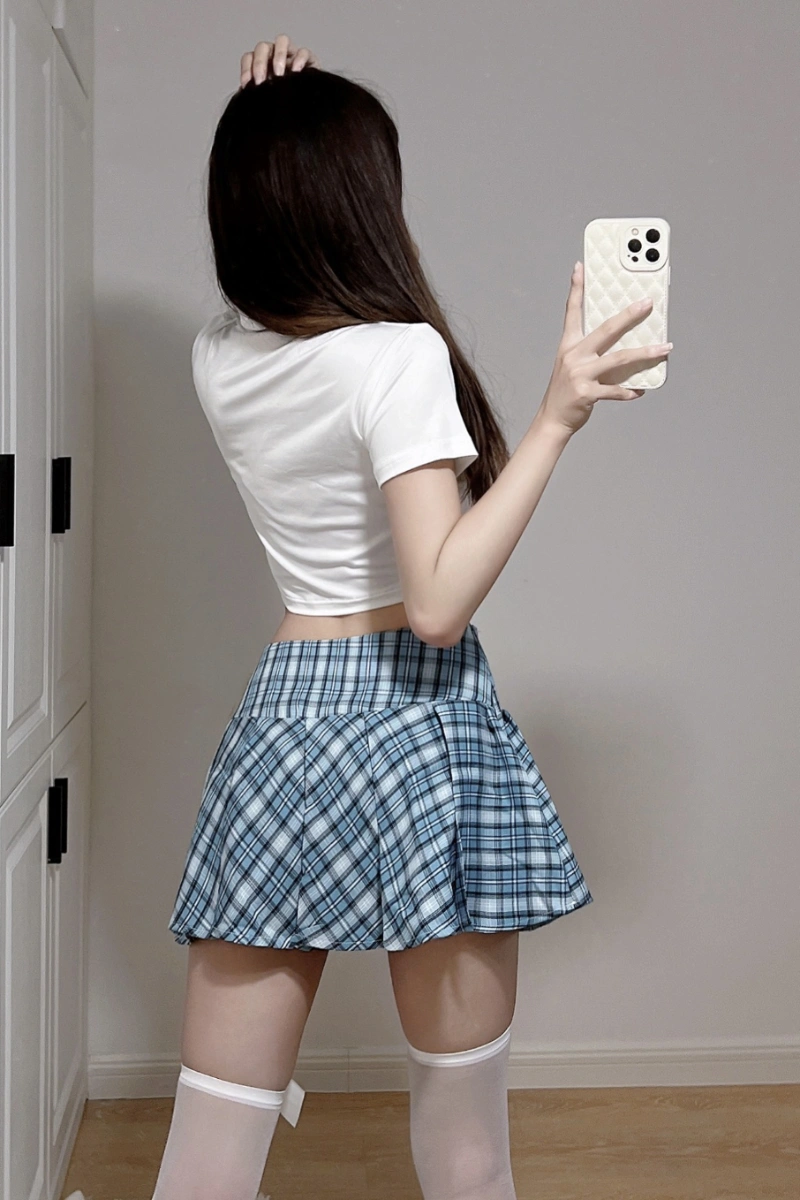 Model wearing wholesale JK school uniform costume featuring a white crop top and blue plaid pleated mini skirt.