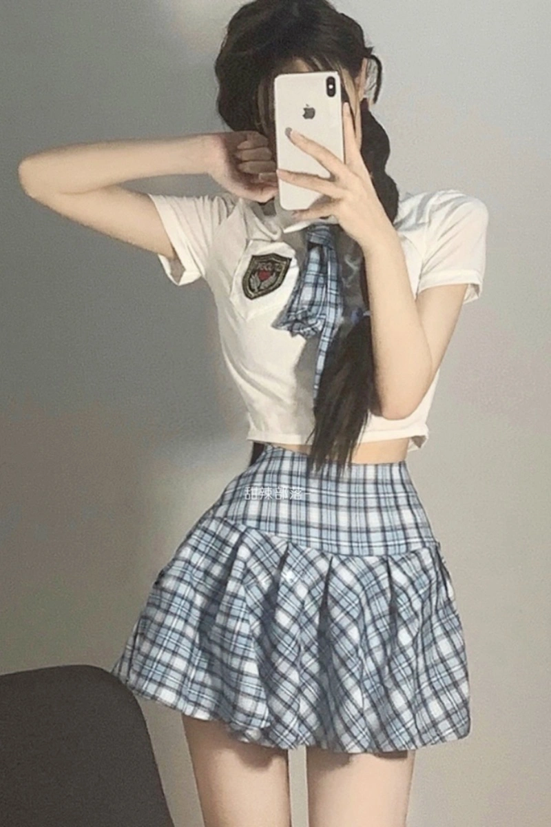 Model posing in wholesale JK school uniform costume with a white short-sleeve top, blue plaid tie, and matching pleated skirt.