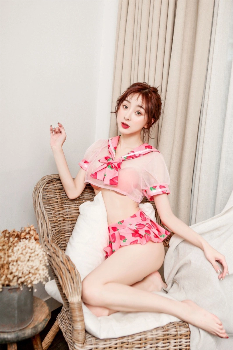Model wearing wholesale sexy student costume in sheer pink with strawberry print accents and mini pleated skirt.