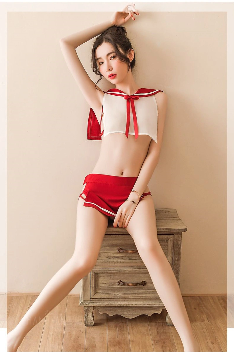 Model dressed in wholesale schoolgirl uniform outfit featuring a cropped white sailor top with red bow and a red pleated skirt