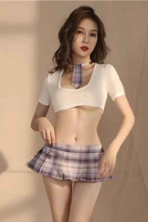 Model wearing wholesale sexy college girl costume featuring white crop top, plaid tie, and pleated mini skirt