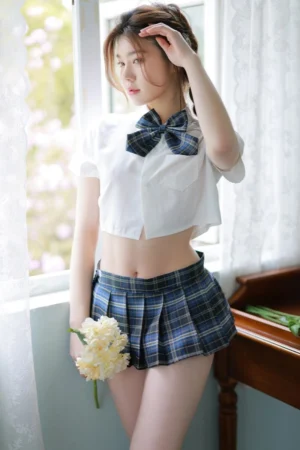Model showcasing a b2b JK mini skirt costume styled with a dark blue plaid skirt, matching bow, and cropped shirt.