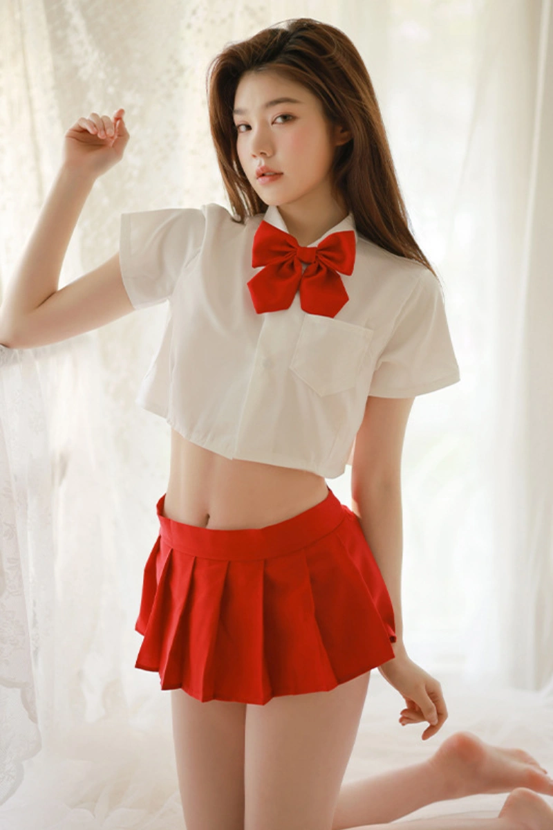 Woman in a b2b JK mini skirt costume with a plain red pleated skirt, red bow, and cropped white shirt.