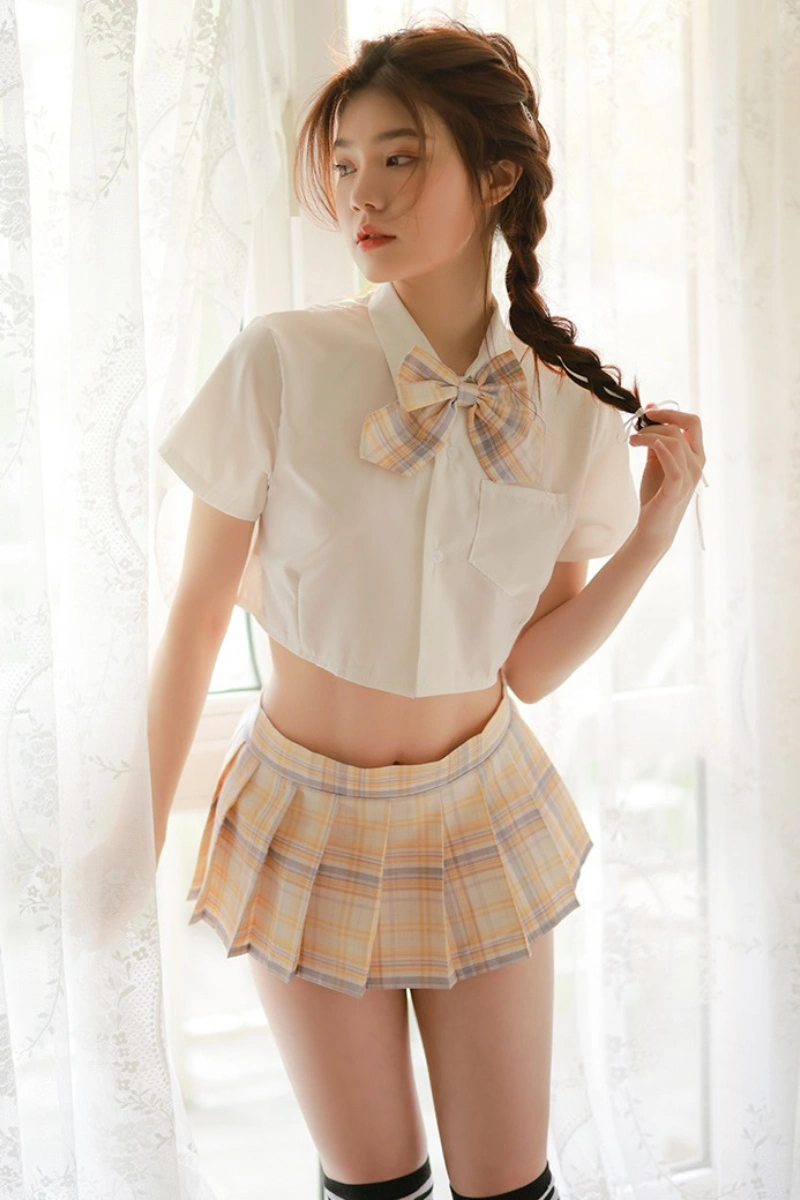 Model dressed in a b2b JK mini skirt costume with a yellow plaid skirt, white cropped shirt, and matching bow.