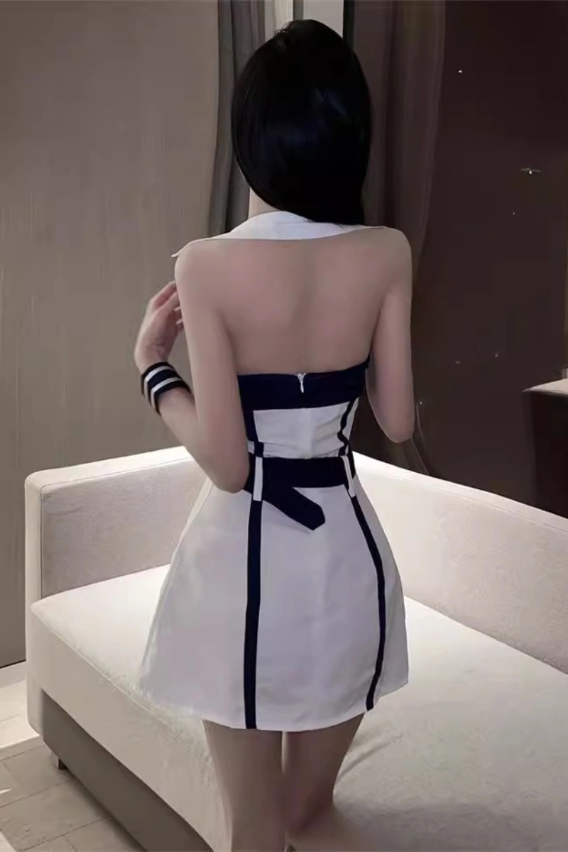 Model wearing a backless b2b student costume in white with navy stripes and bow tie detail