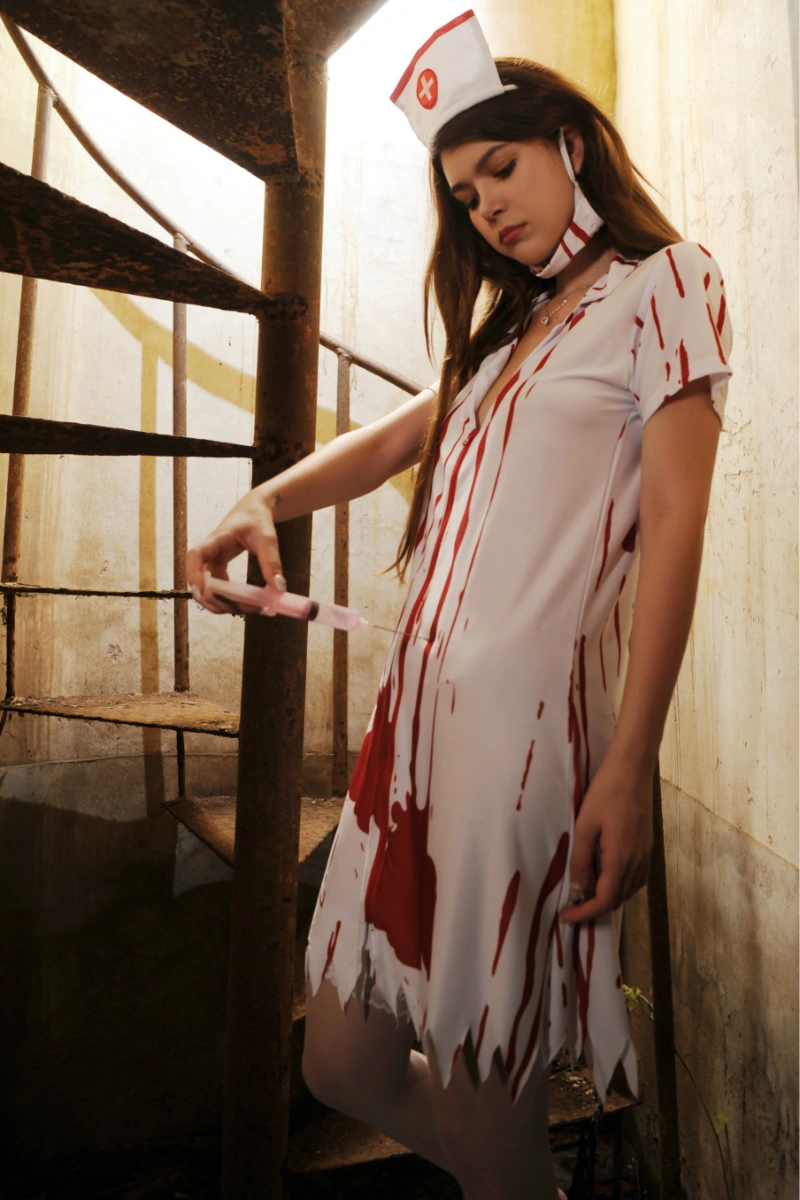 Model in Bloody Nurse Costume with red blood print and syringe prop, wearing white thigh stockings.