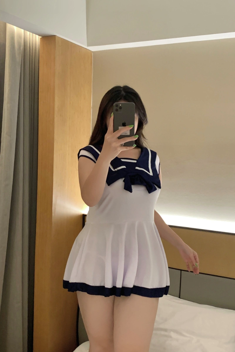 Front view of schoolgirl costume with navy blue sailor collar and large bow on a white short dress.