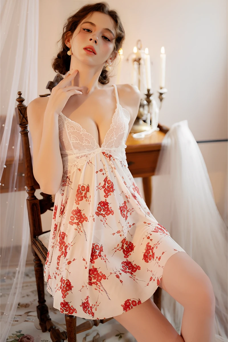 Model wearing bulk lace pajama nightwear featuring a white lace bodice and red floral sheer skirt in a romantic bedroom setting