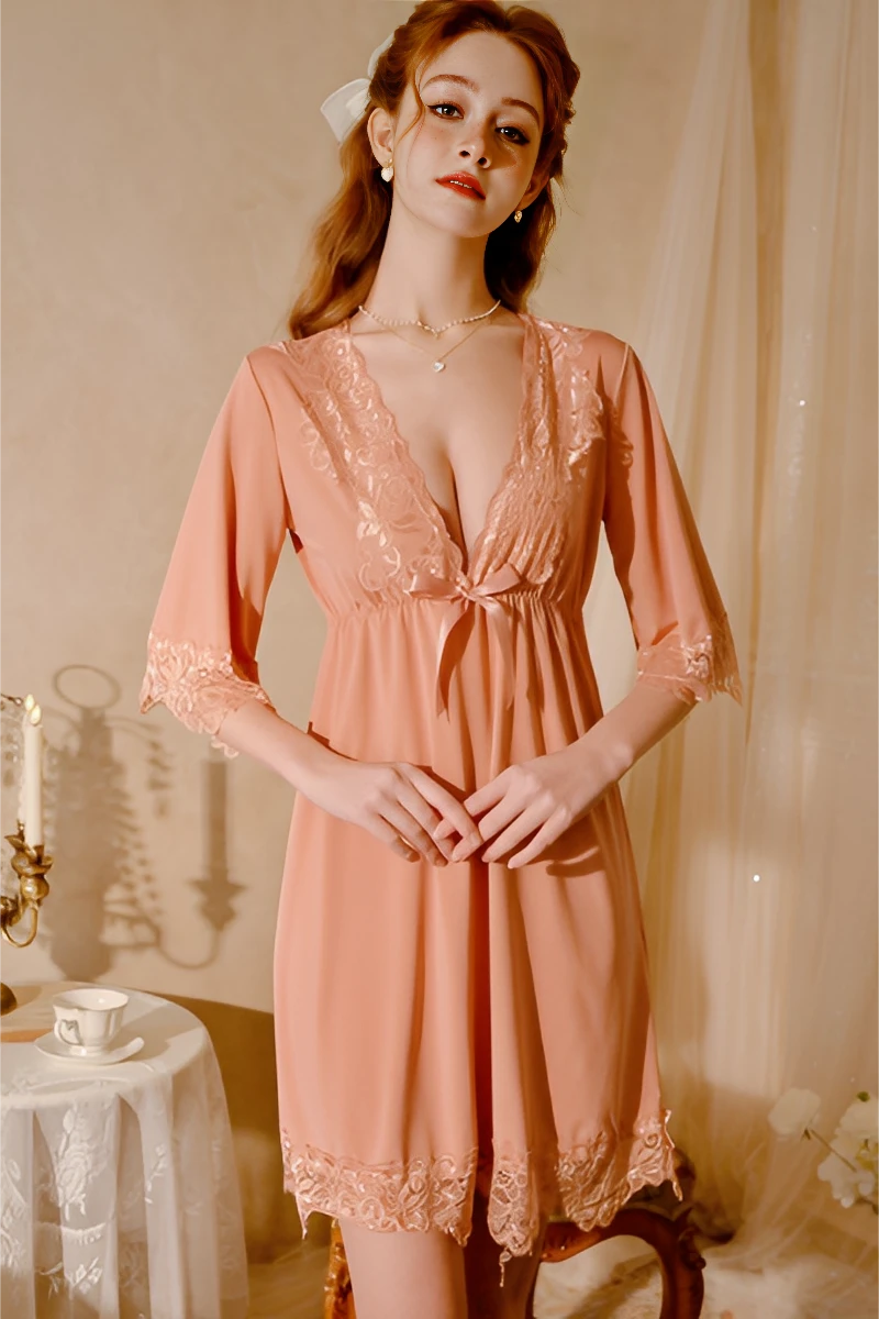 Model wearing a peach tone bulk lace pajama with deep V neckline, half sleeves, and lace trim in a soft romantic bedroom setting