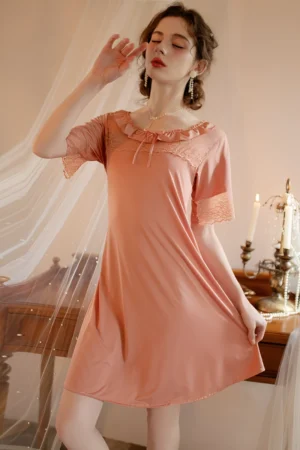 Model wearing bulk women's sexy solid color lace pajamas in soft pink with lace trim neckline and flowing short sleeves.