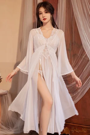 Model wearing a custom sexy silk nightgown in white with sheer lace bodice and flowing long robe in a bridal bedroom setting