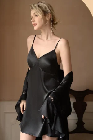 Model wearing a black satin slip dress with lace cuffs and matching robe, showcasing an elegant oem nightgown sexy design for women.