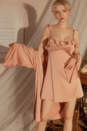Model wearing a soft pink satin slip nightdress with ruffle trim and matching robe, styled as a wholesale sexy chic nightgown