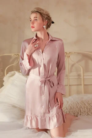 Model wearing pink satin button-up sexy nightgown women style with long sleeves, waist tie, and soft feminine silhouette