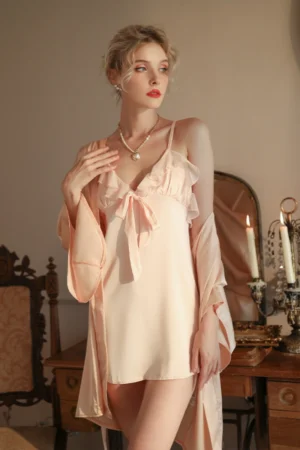 Model wearing a soft pink satin slip nightgown with bow detail and matching robe, shown as a b2b sexy lingerie nightgown