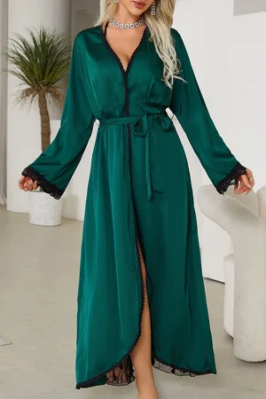 Model wearing emerald green wholesale sexy nightgowns for women with lace trim, waist tie, and flowing long silhouette in a modern indoor setting