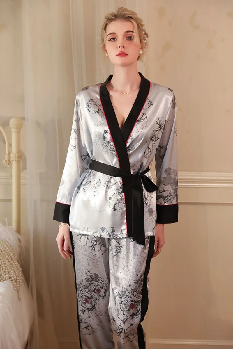 Model wearing a wholesale sexy white nightgown style pajama set with floral satin fabric, long sleeves, and waist tie design